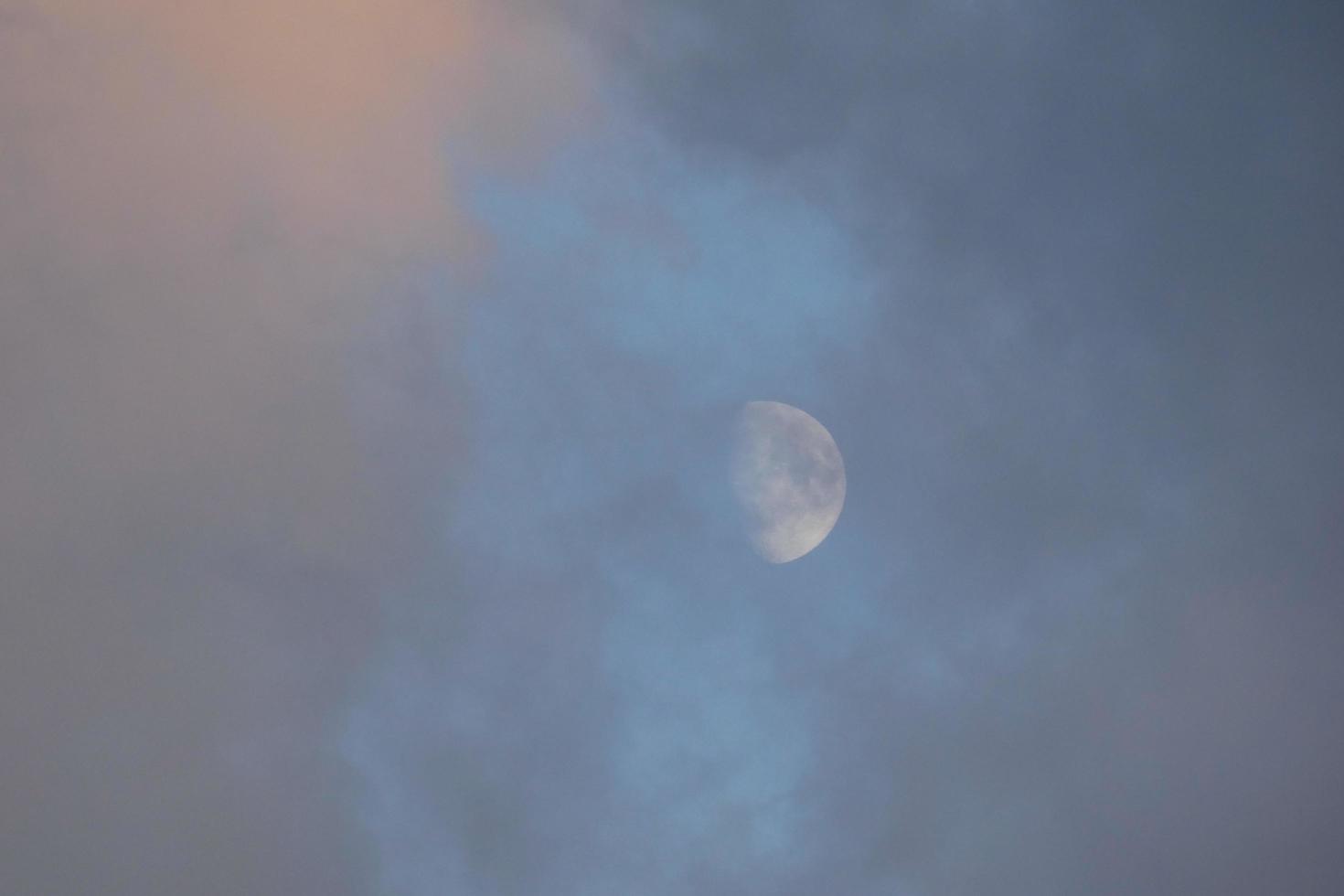 Near-full moon, seen through the clouds at sunset. photo