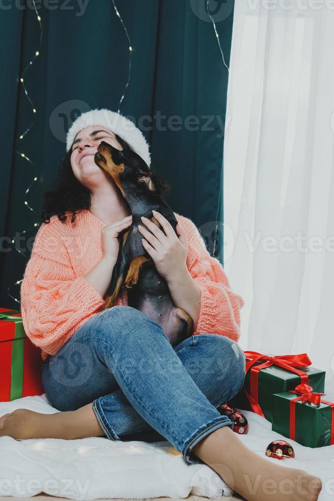 Portrait of young woman playing with funny dog miniature pinscher photo