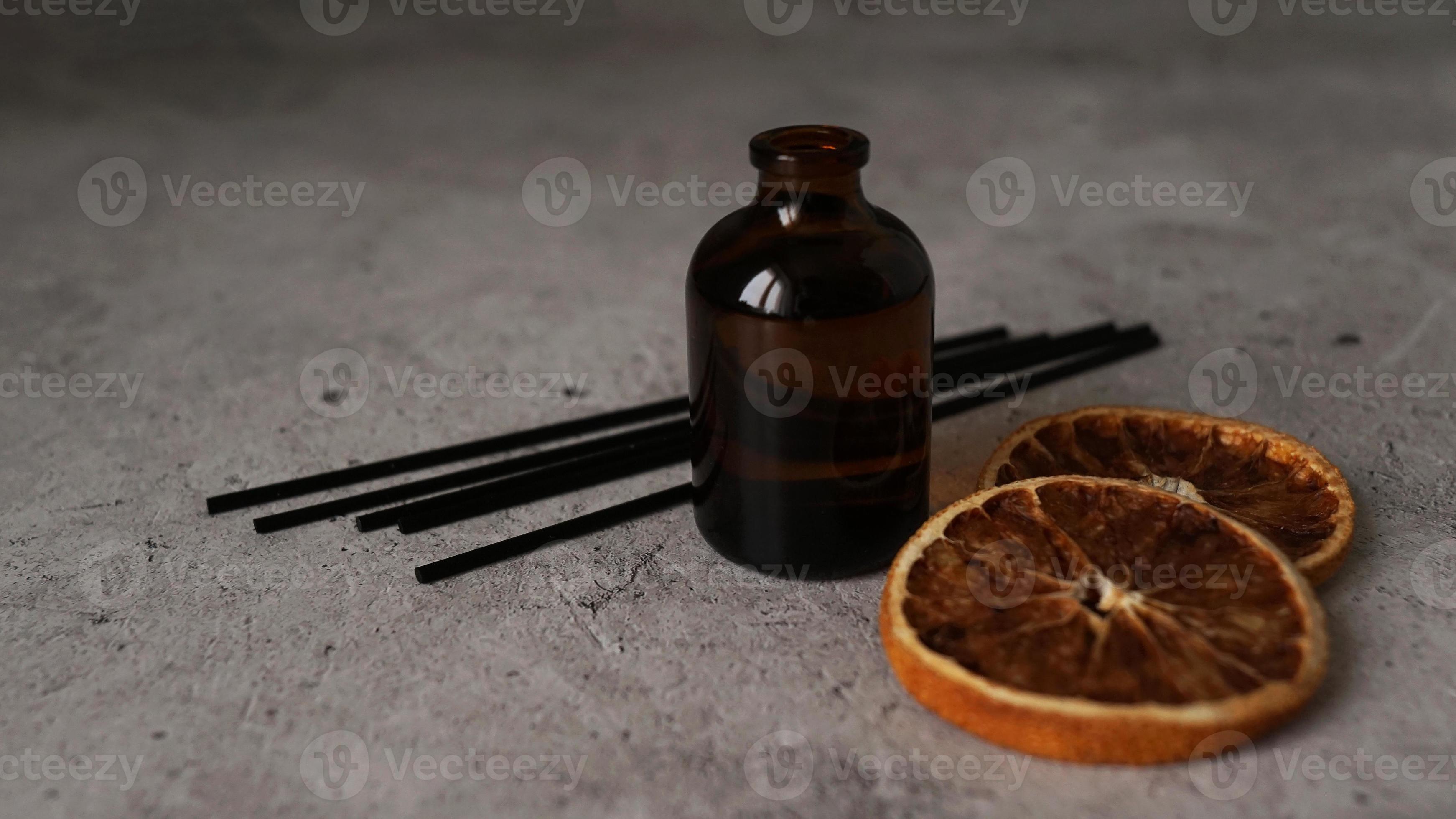 Citrus reed diffuser on dark background. Bottle, sticks and dry oranges