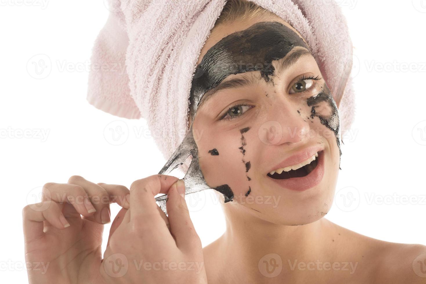 Black facial mask. beautiful girl piling off black mask. beauty concept photo