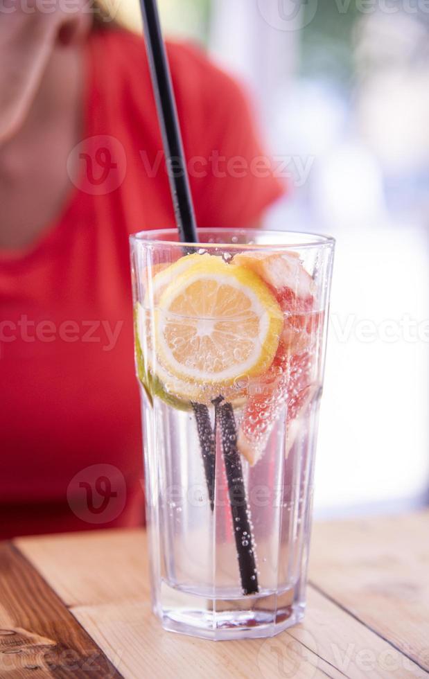 primer plano de una mujer disfrutando de un cóctel mojito tropical decorado con fruta fresca foto