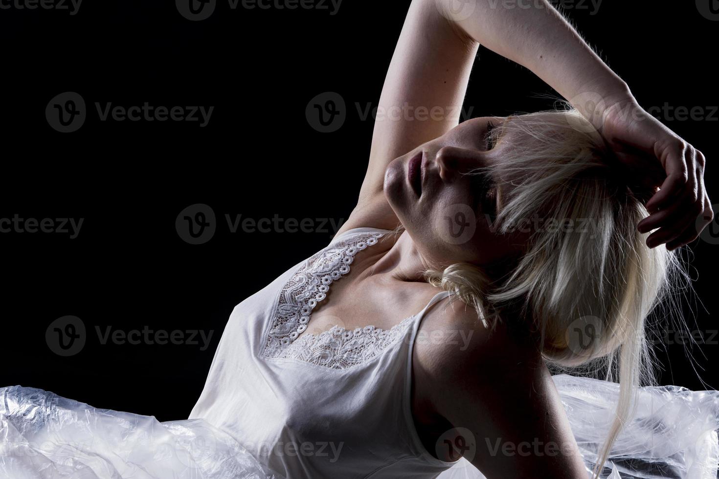 Silhouette of a Beautiful blond woman wearing white nightgown posing on black  background. photo