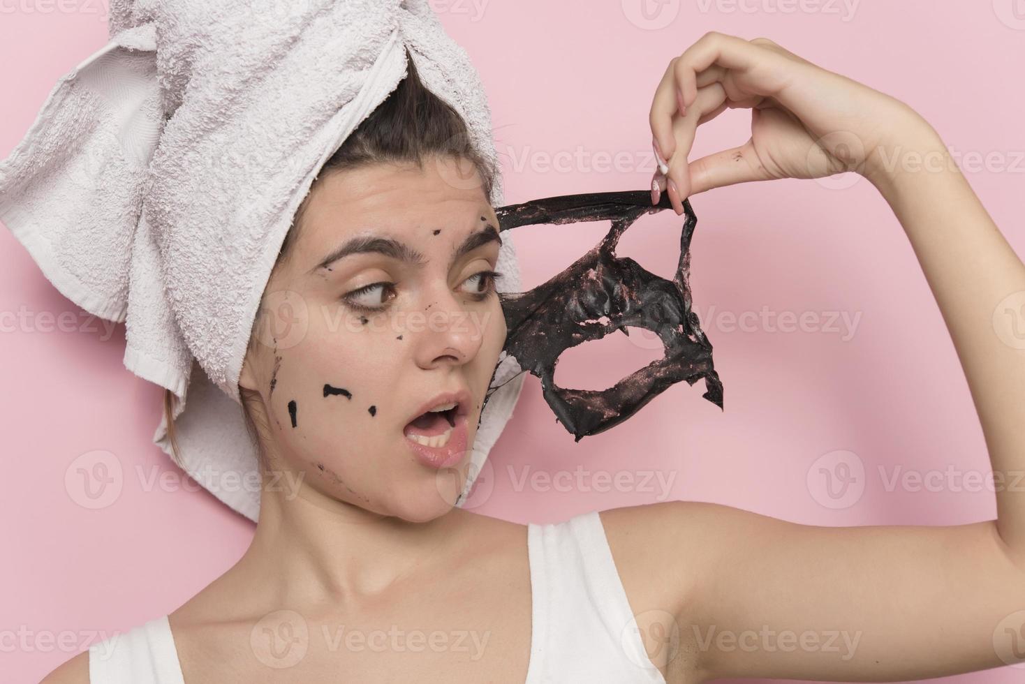 Beautiful smiling woman piling off black cosmetic mask from her face. Beauty concept. isolated photo