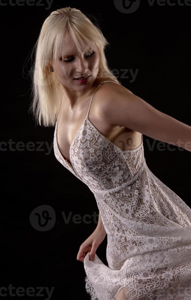 Silhouette of a Beautiful blond woman wearing white nightgown posing on black  background. photo
