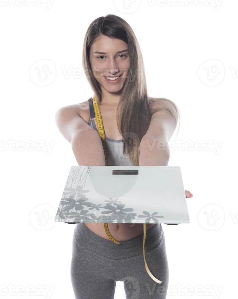 Female model holding scale and measuring tape over white background photo