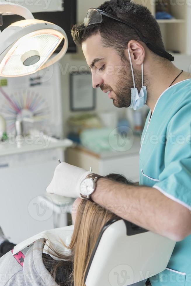 dentista curando los dientes del paciente llenando la cavidad. dentista que trabaja con equipo profesional en la clínica. foto