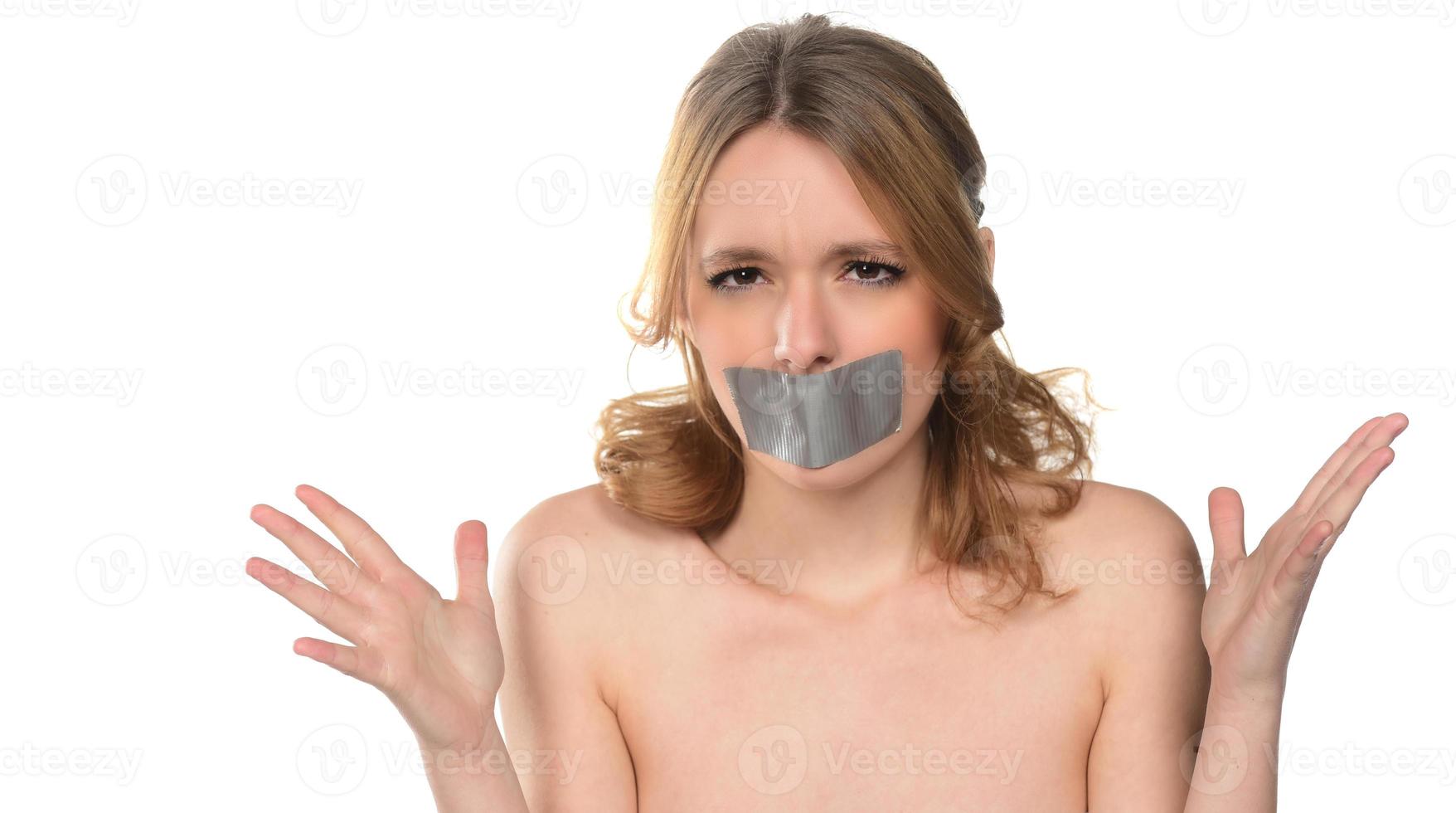 scared young woman with tape over her mouth. photo