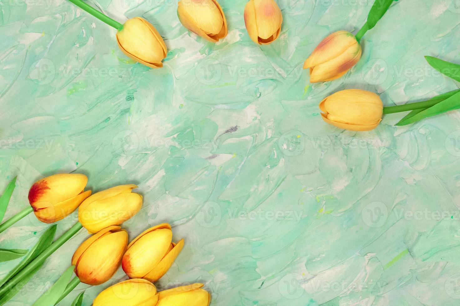 Yellow tulips are arranged out of corner and in arc. There is place for text on green mint background with brush strokes. Postcard Happy Easter, March 8, International Woman's Day photo