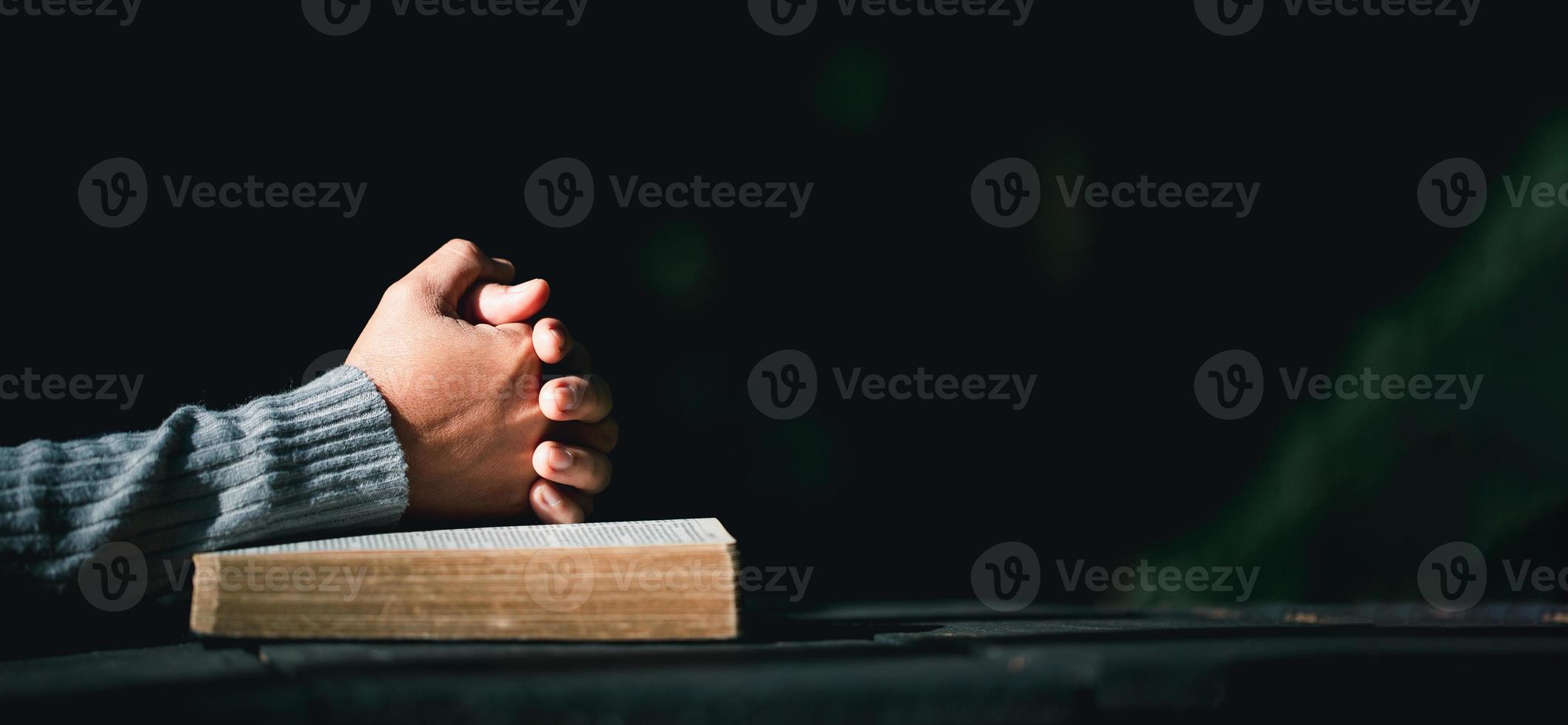 mano de persona de oración en fondo negro. la mujer católica cristiana está rezando a dios en la oscuridad en la iglesia. chica cree y fe en jesucristo. la religión de cristo y el cristianismo adoran o rezan concepto. foto