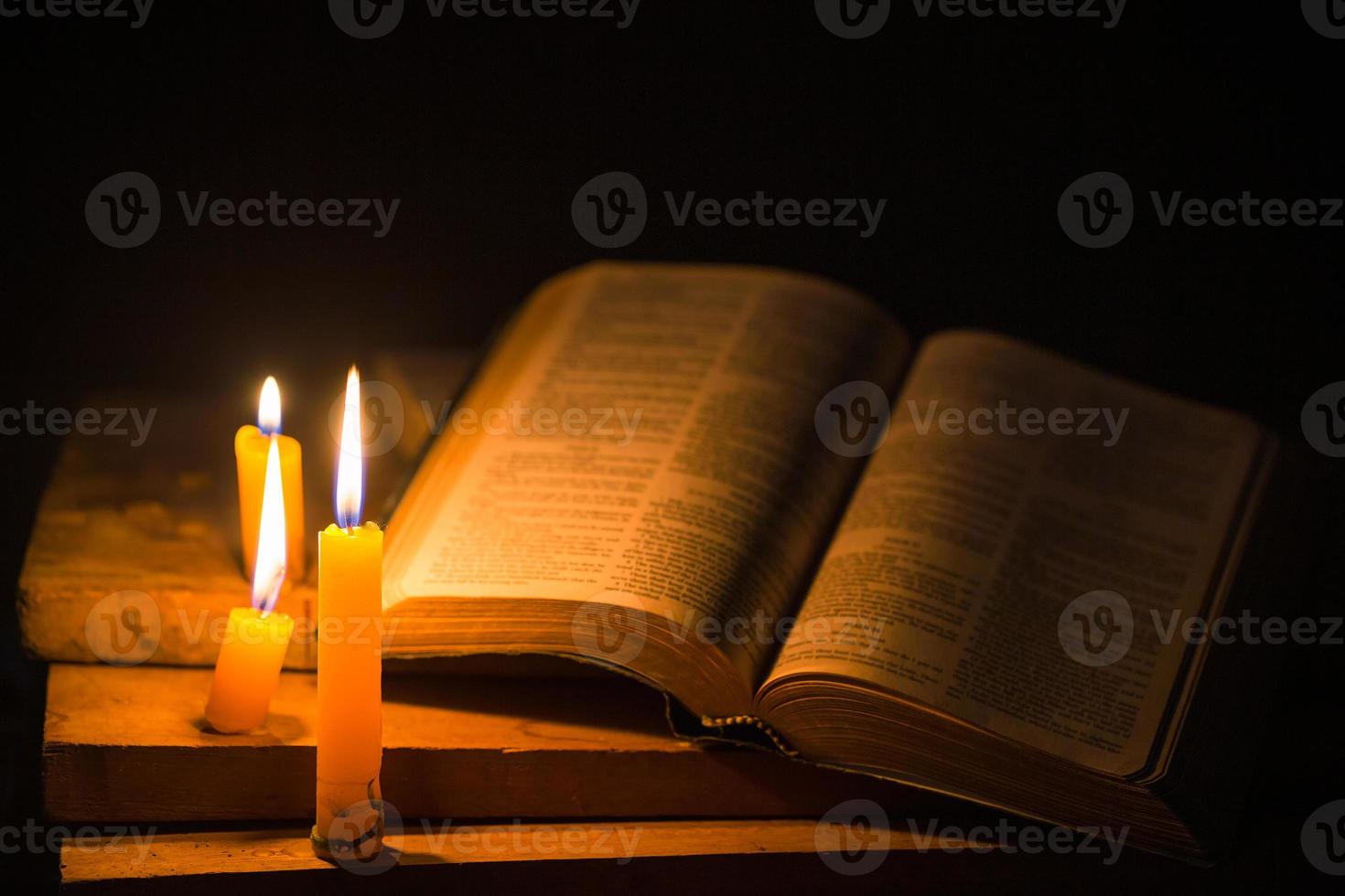Light candle with holy bible and cross or crucifix on old wooden background in church.Candlelight and open book on vintage wood table christianity study and reading in home.Concept of christ religion photo