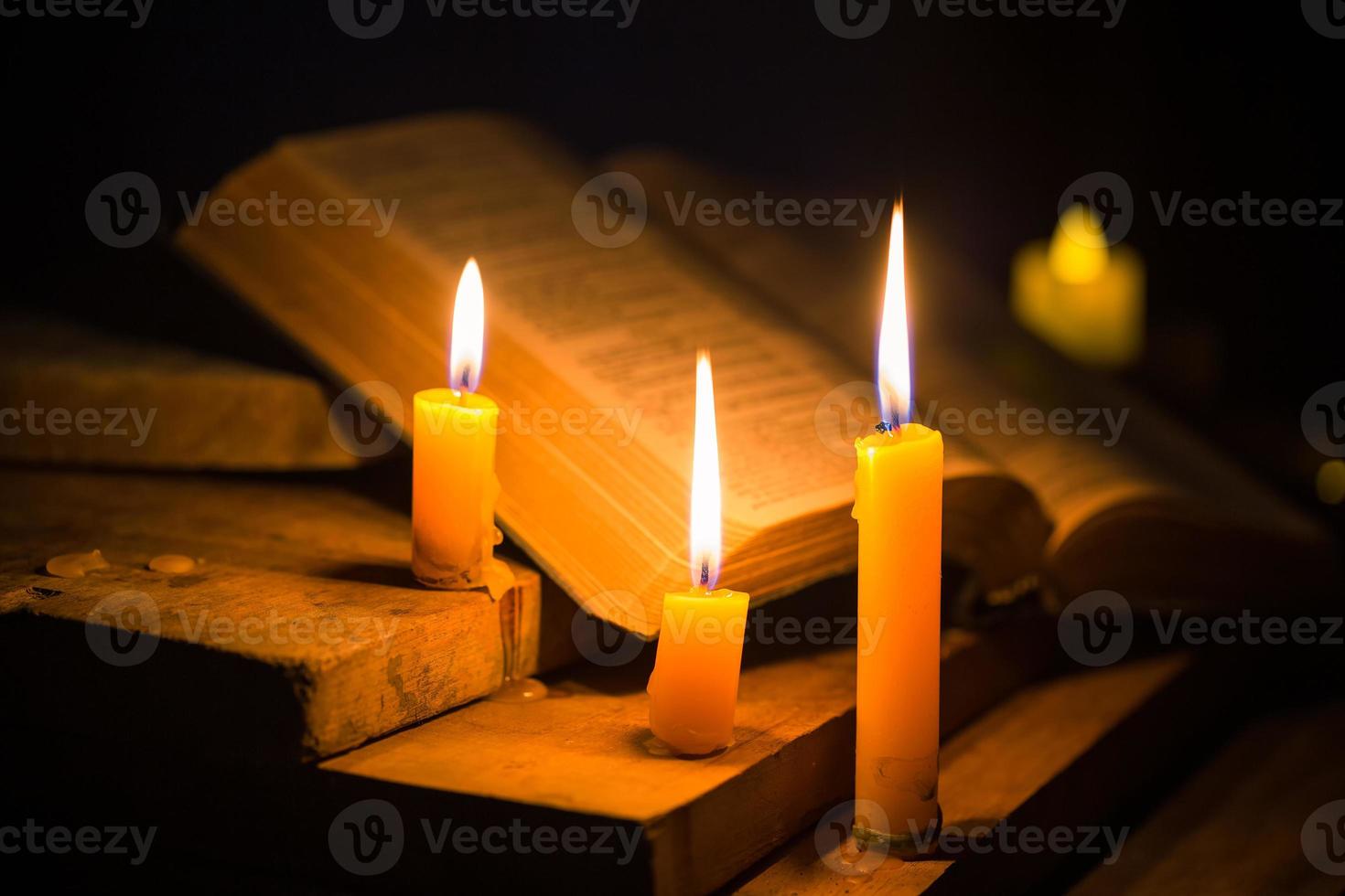 Light candle with holy bible and cross or crucifix on old wooden background in church.Candlelight and open book on vintage wood table christianity study and reading in home.Concept of christ religion photo