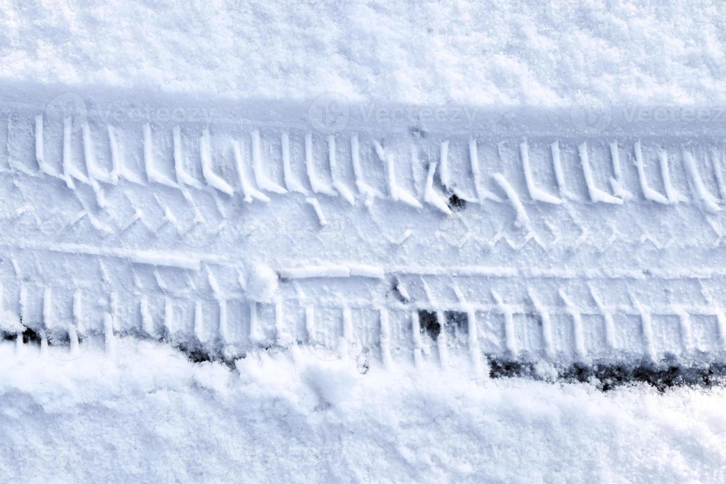 Close up view tire tracks at the surface of fresh fallen snow. photo