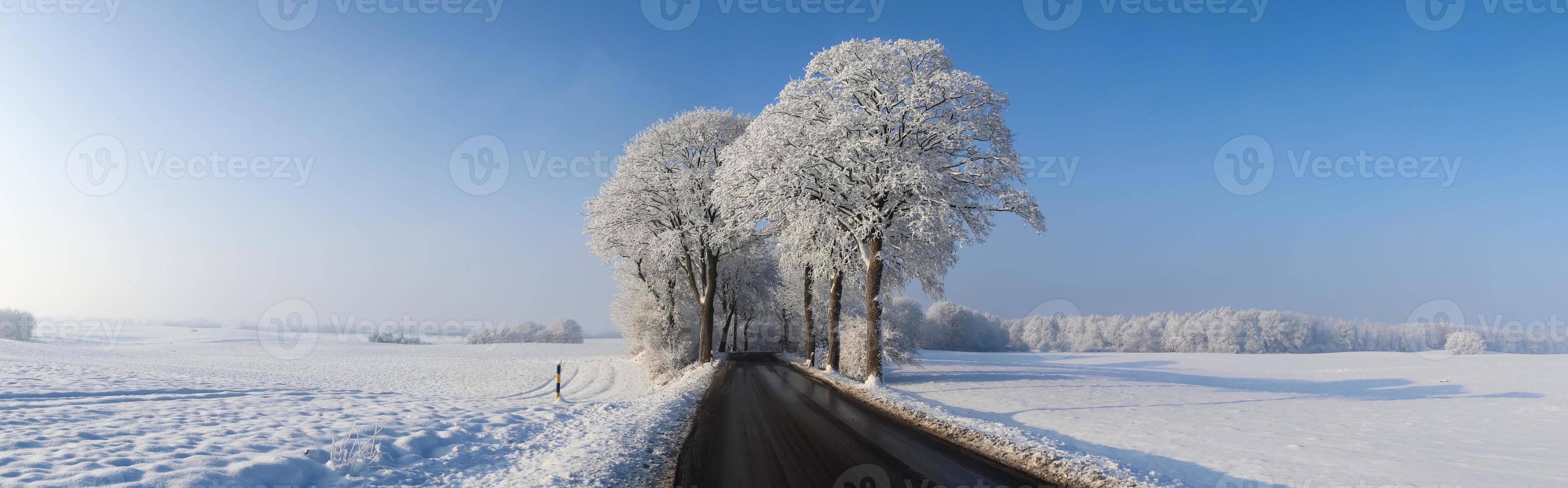 View of a snow-covered country road in winter with sunshine and blue sky. photo