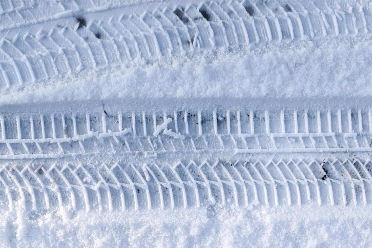 Close up view tire tracks at the surface of fresh fallen snow. photo
