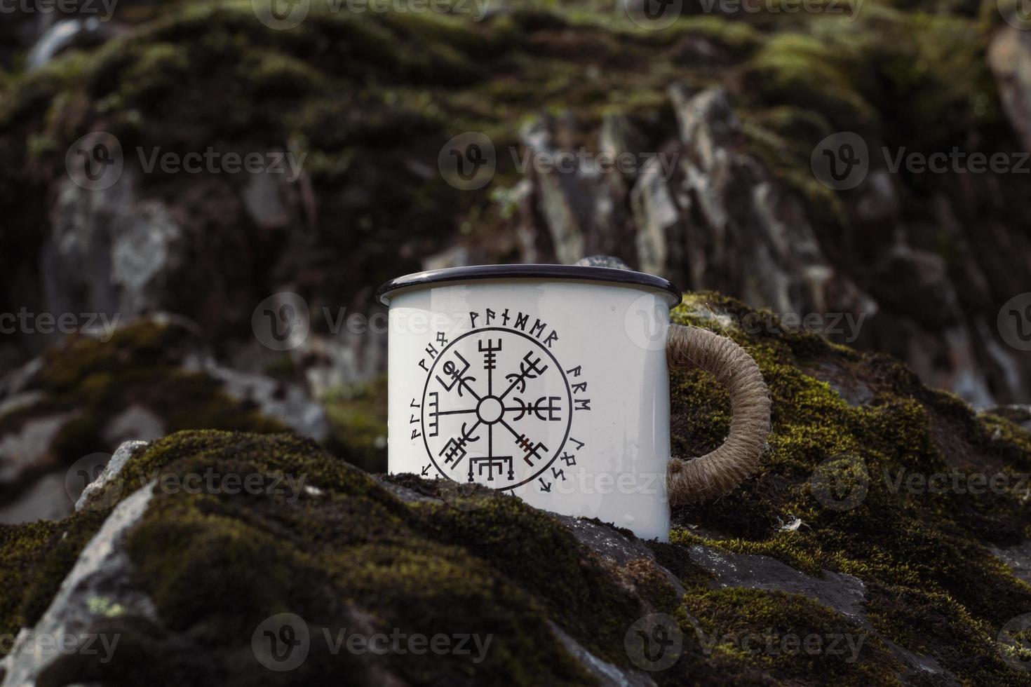 Close up enamel mug with runes on rock concept photo