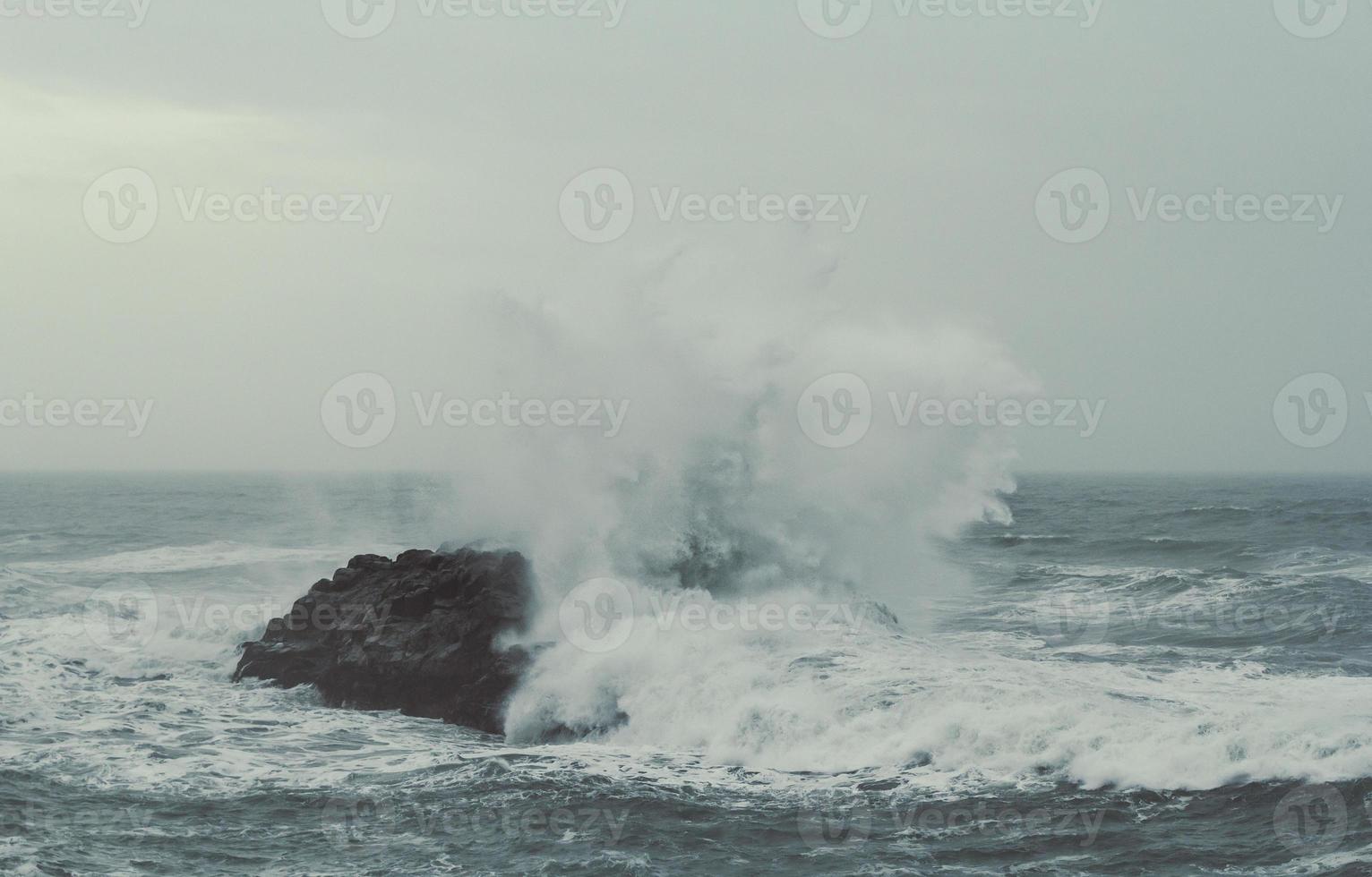 Splash sea water over rock on storm landscape photo