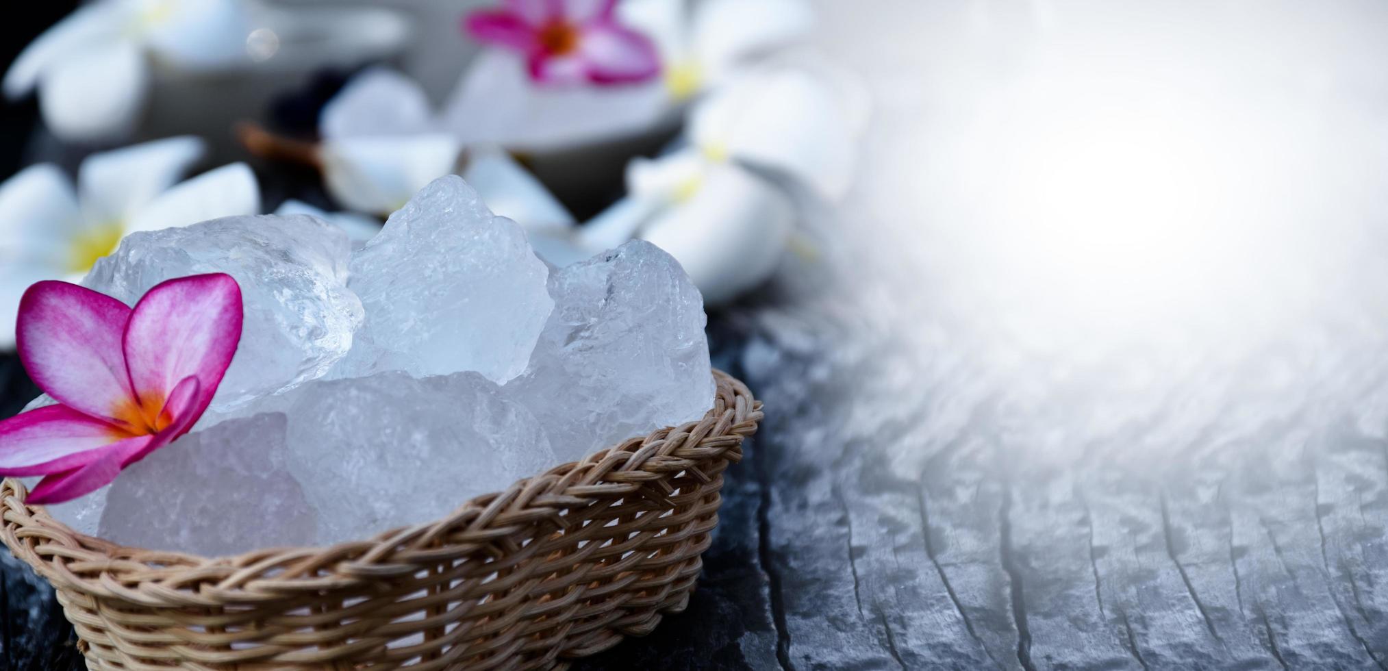 Soft focus of Alum cubes and plumeria flower on small wicker basket, blurred background, concept for herb, bodycare, skincare, waterclear, spa, treatment, disease protection and protect armpit smell. photo