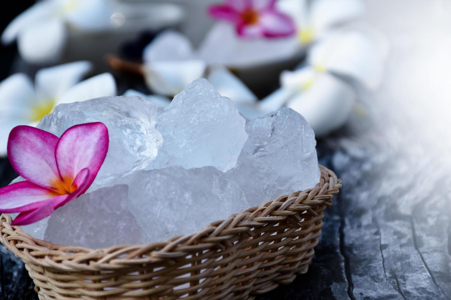 Soft focus of Alum cubes and plumeria flower on small wicker basket, blurred background, concept for herb, bodycare, skincare, waterclear, spa, treatment, disease protection and protect armpit smell. photo