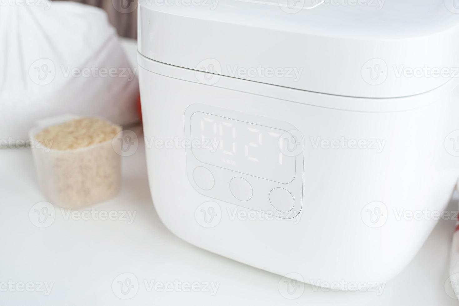 Electric rice cooker on wooden counter-top in the kitchen photo