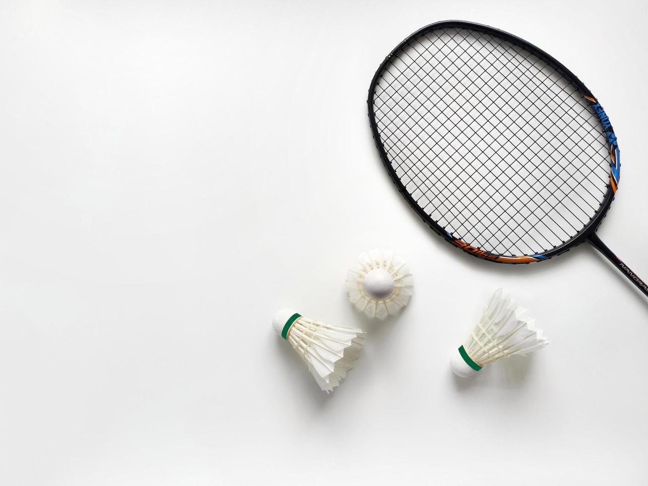 Three shuttlecocks with a racket on a white background with wide white space for free text. Top view photo