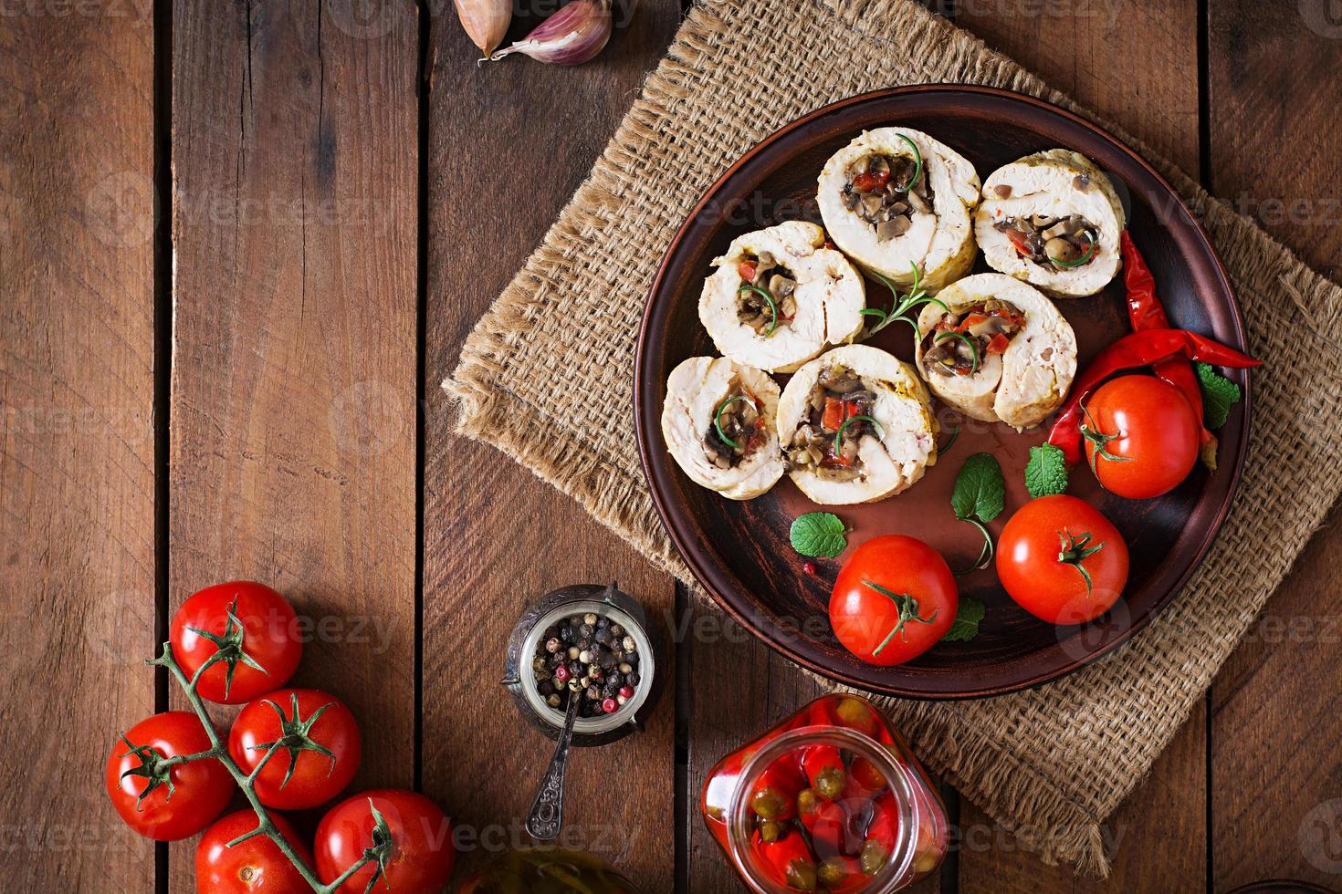 Baked chicken rolls with mushrooms and paprika on brown plate. Top view photo