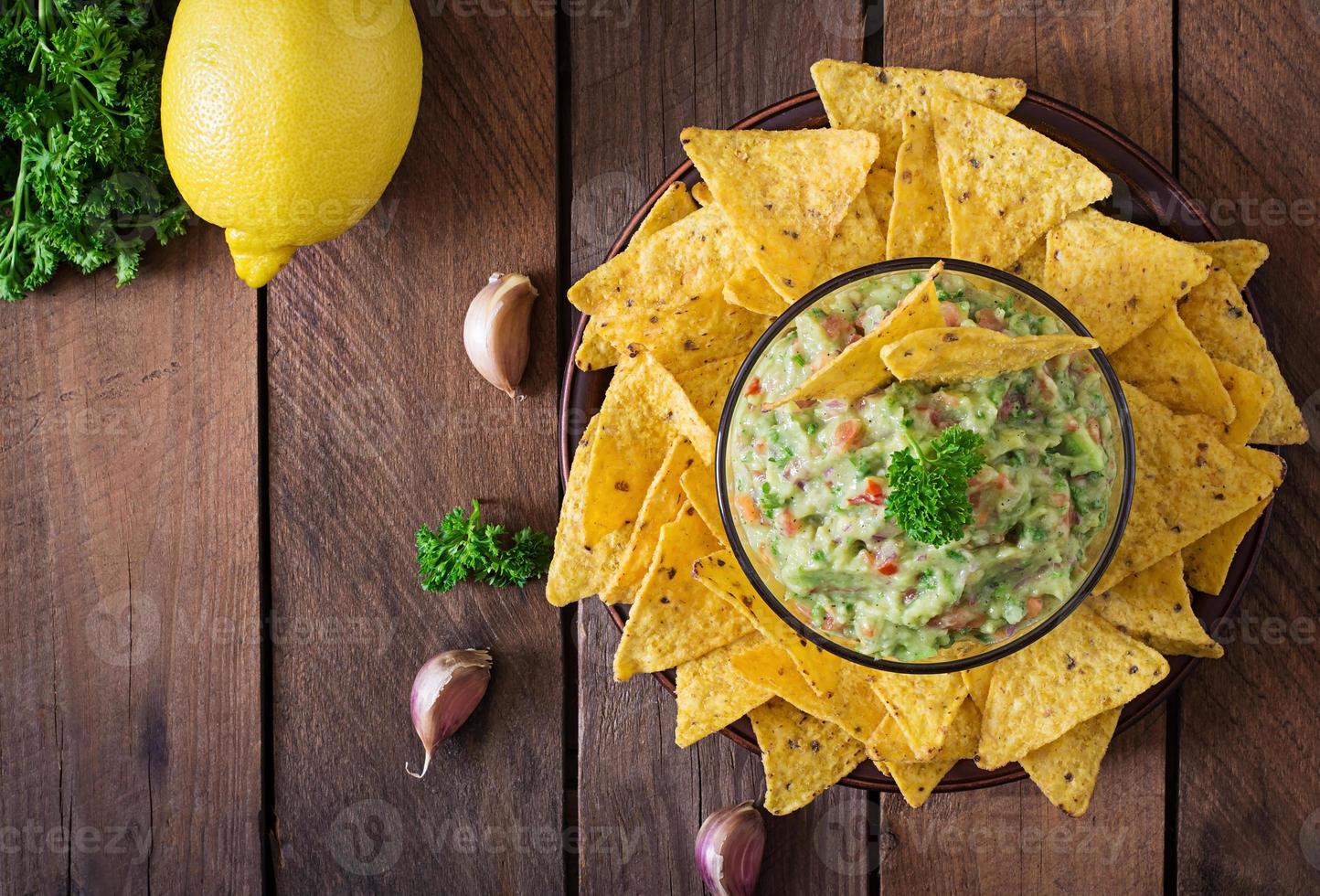 aguacate guacamole, lima, tomate, cebolla y cilantro, servido con nachos - merienda tradicional mexicana foto