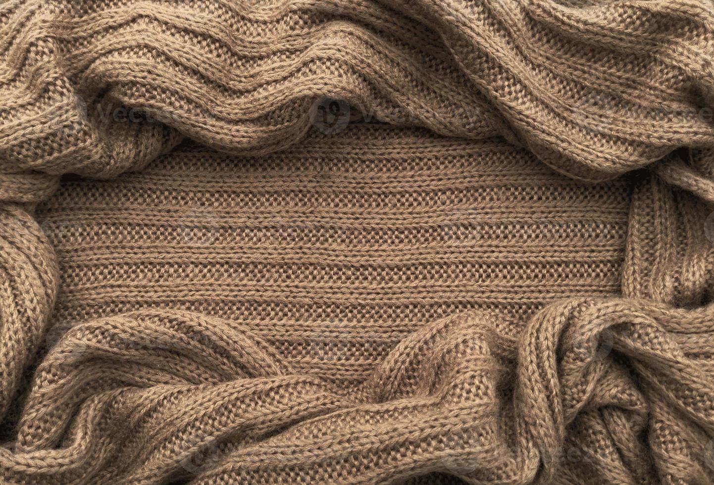 Oval frame for text from brown knitted scarf or sweater texture, top view. Texture background of warm crocheted clothing textile. Knitwear fabric. photo