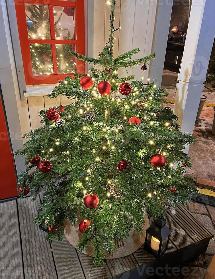 A beautiful small Christmas tree decorated with shiny balls and a shiny light garland. Perfect content for advertising banners, gift card or creative projects. photo