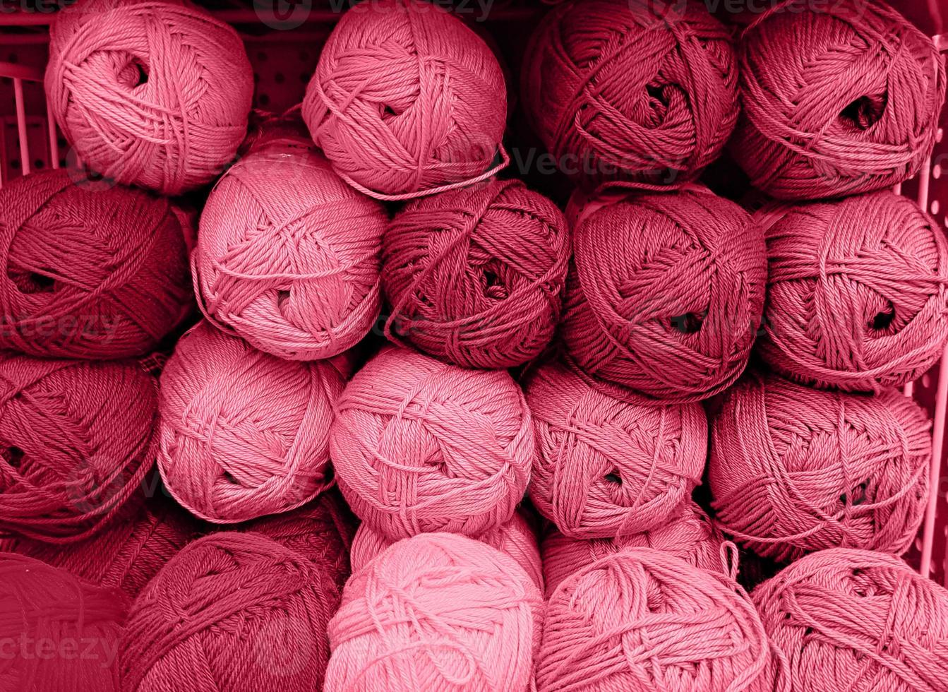 ovillos de lana en una tienda de telas. fondo de hilo acrílico de colores. madejas de primer plano de hilo. materiales para costura, para tejer y ganchillo. color del año 2023 - magenta viva foto