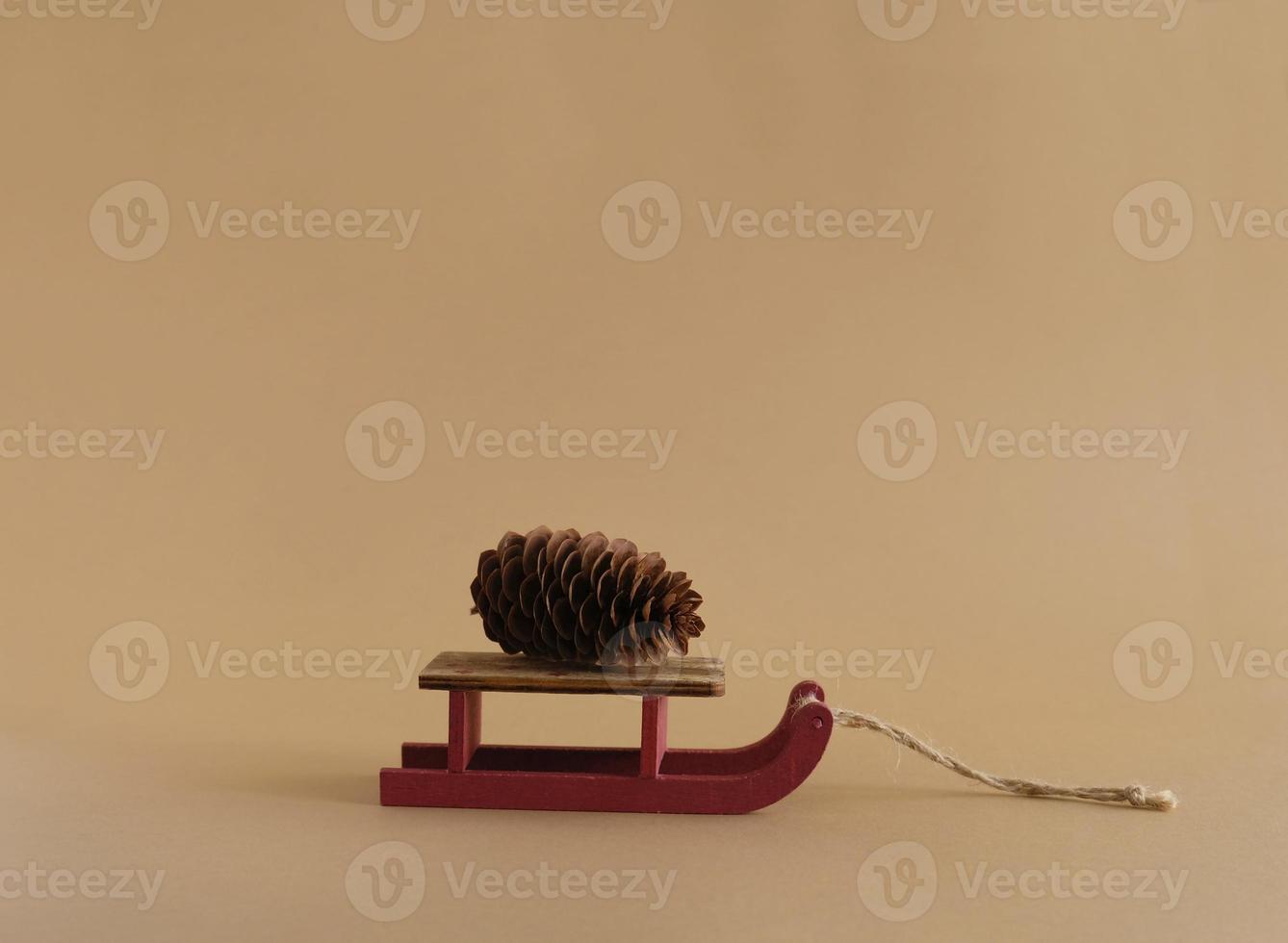 Decorative wooden red sleds with a pine cone. Colored pastel background. Copy space. Winter and christmas design template greeting card. photo