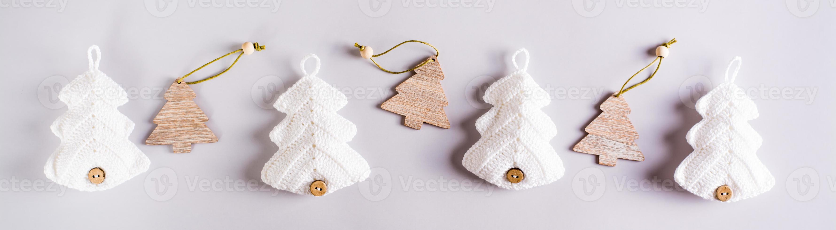 Knitted and wooden fir trees in a row on a gray background. Web banner photo