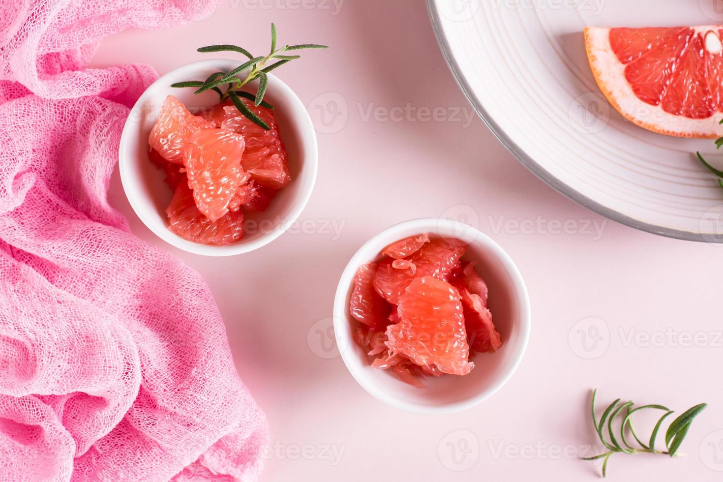 Peeled pieces of grapefruit and rosemary in a bowl on the table. Cocktail ingredients. Top view photo