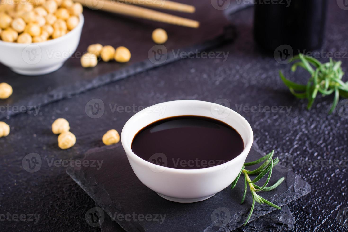 Soy sauce in a bowl and soy beans on the table. photo
