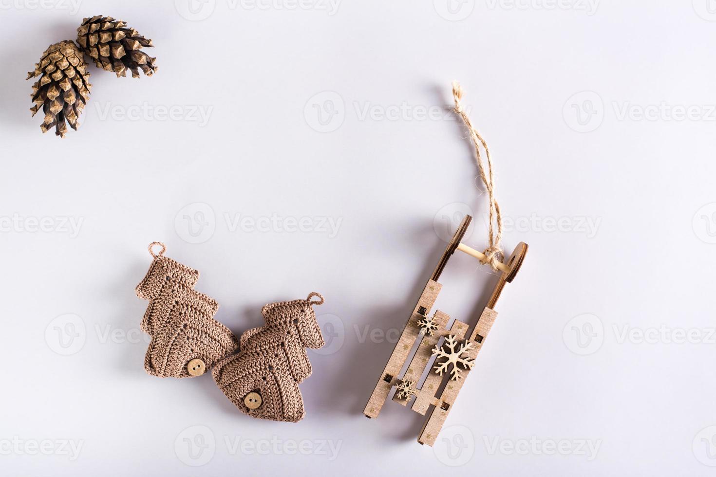 Two knitted fir trees, wooden sled and pine cones on a gray background. Handmade Christmas decor photo