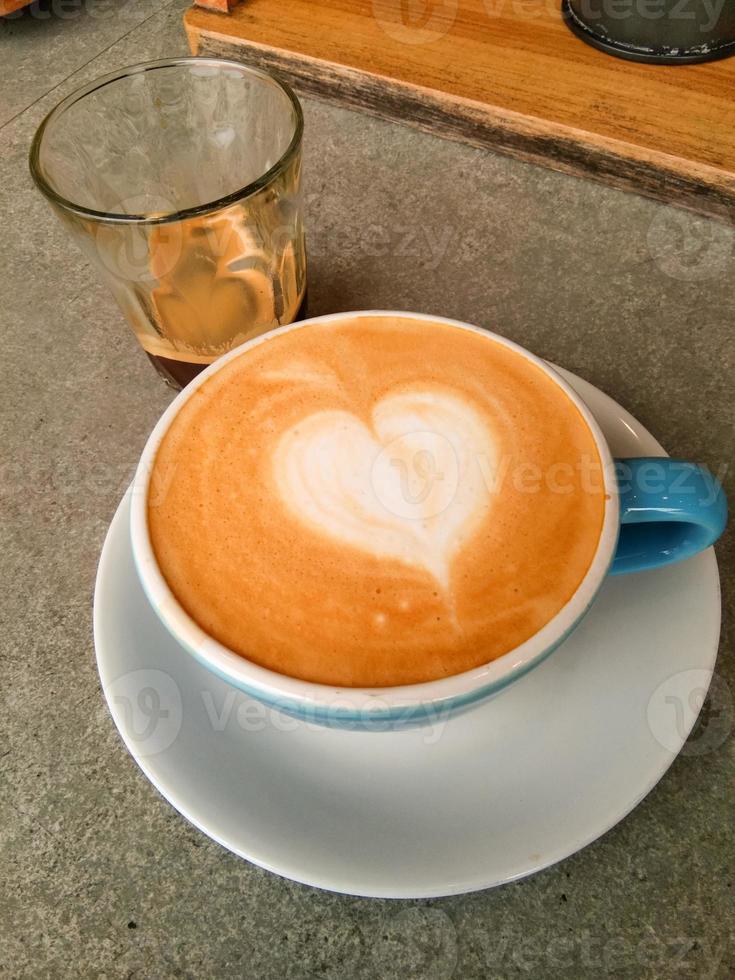 Cup of hot cappucino is on the wooden table. It is an art on the latte. photo