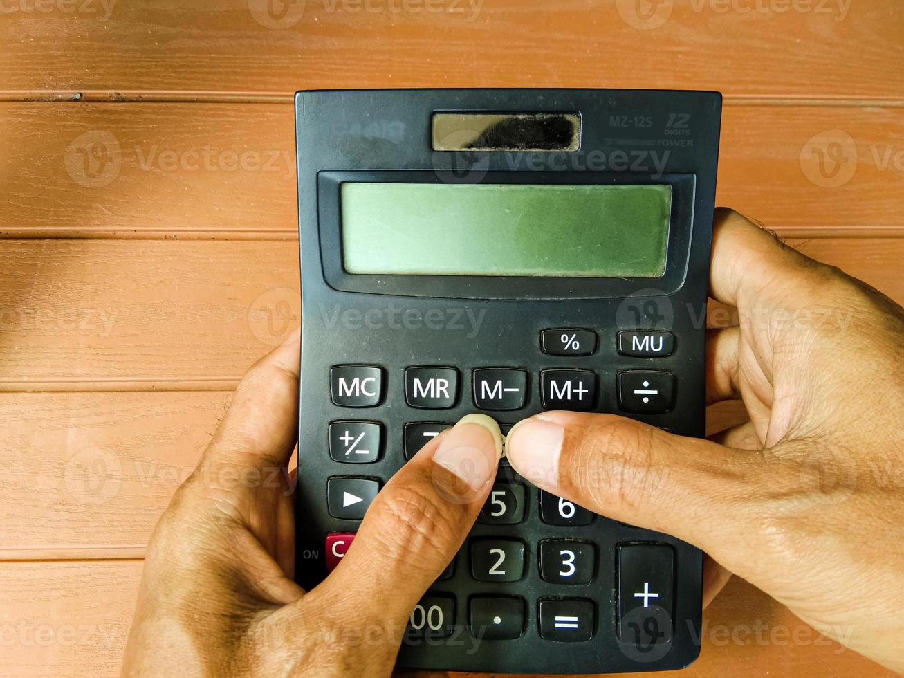 businessman hand working with calculator on wooden table photo