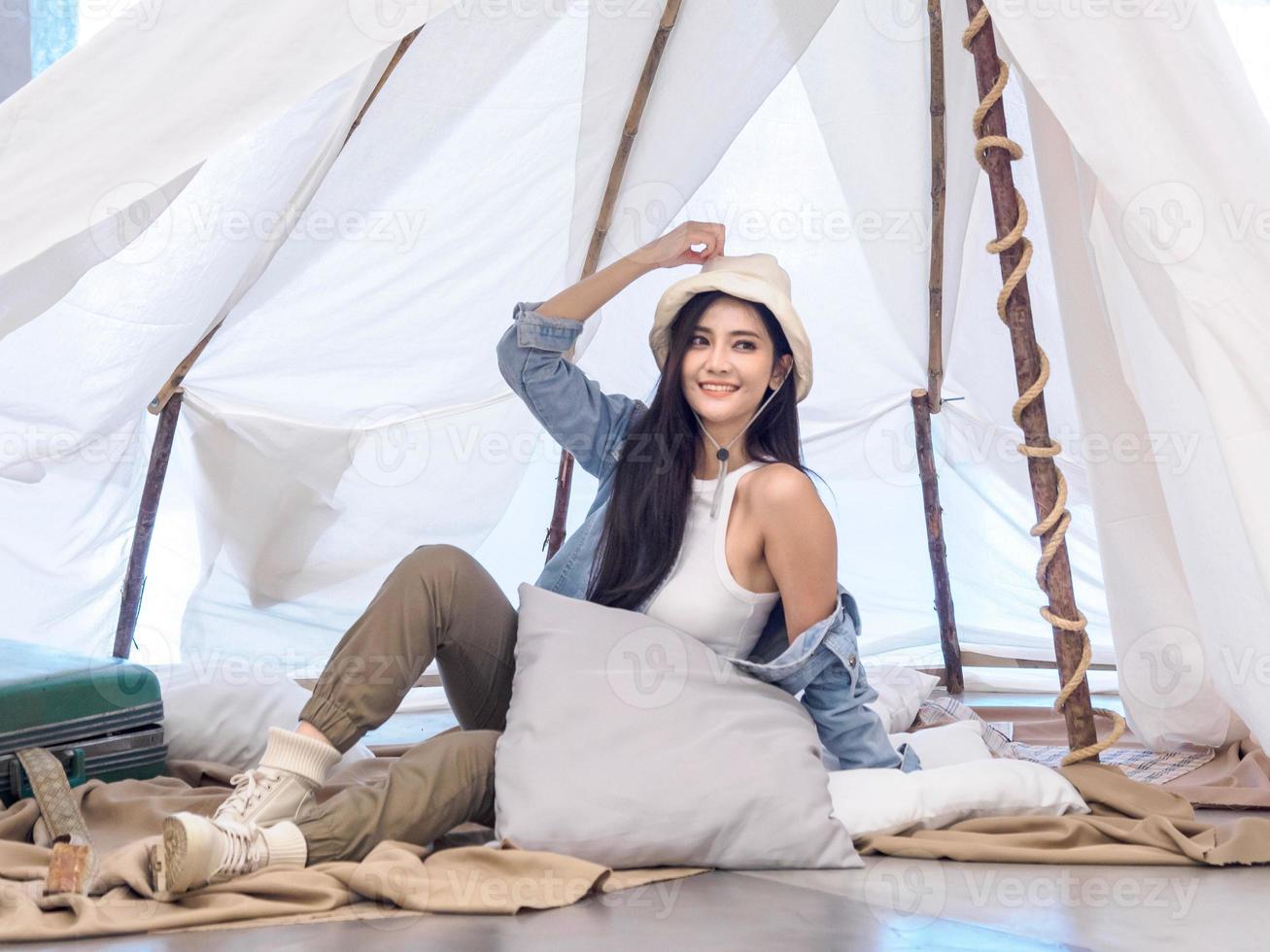 Portrait beautiful young girl woman Asian pretty smile one person alone sitting on chair camping with teble flower in vase lantern red travel trip in front tent freedom relax happy enjoy in vacation photo