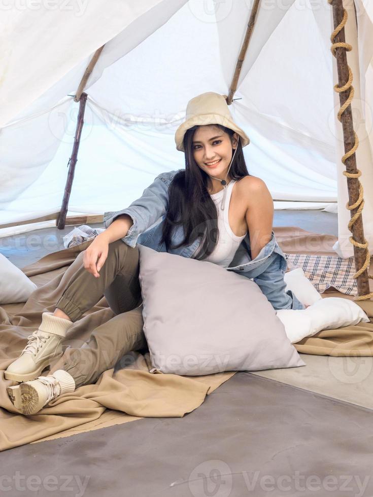 Portrait beautiful young girl woman Asian pretty smile one person alone sitting on chair camping with teble flower in vase lantern red travel trip in front tent freedom relax happy enjoy in vacation photo