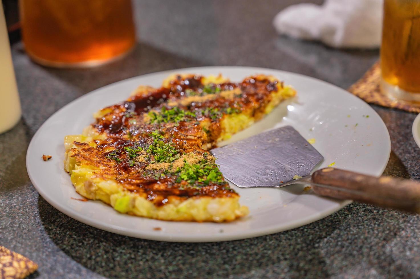 okonomiyaki comida tradicional japonesa en restaurante japonés.okonomiyaki conocido como pizza tradicional japonesa foto