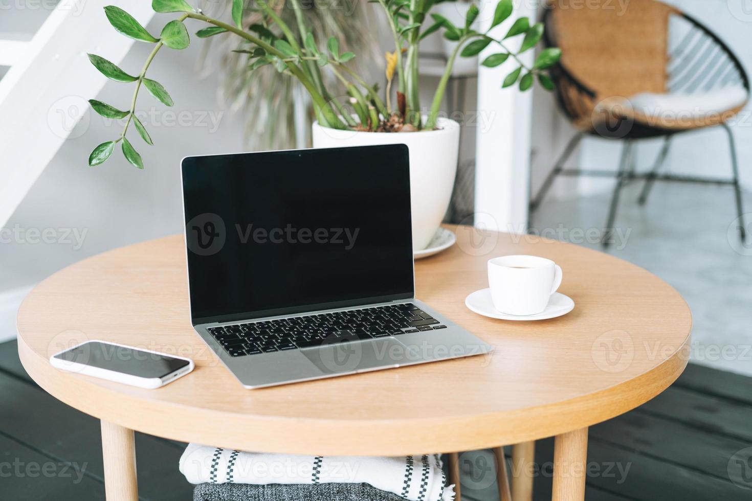 Working place with cup of coffee, open laptop on wooden table in room photo