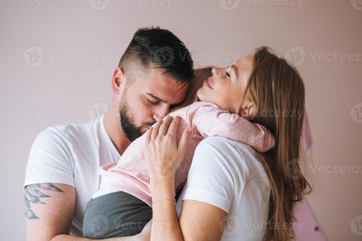 Happy multinational family father young man and mother with baby girl little daughter having fun in children room at home photo