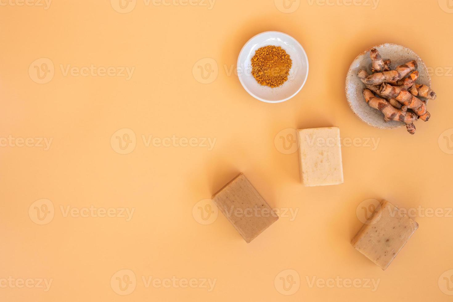 Top view of turmeric and bar soap on orange pastel background. Spa background concept. photo