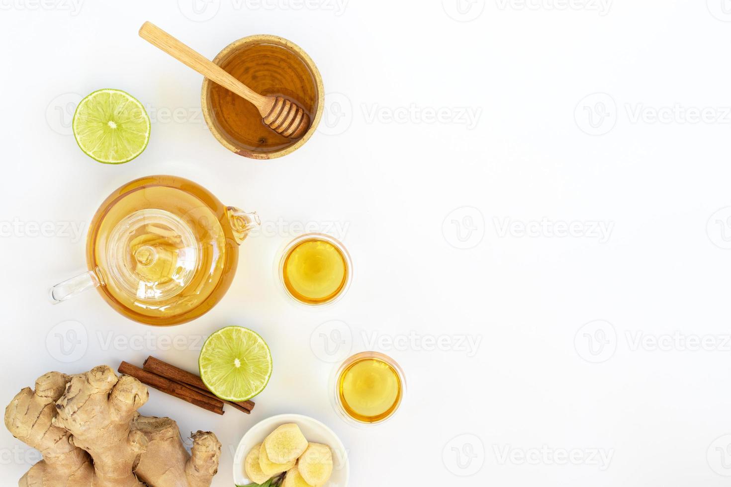 vista superior de una taza de té con raíz de jengibre, lima, canela y tetera sobre fondo blanco. concepto de bebida saludable foto