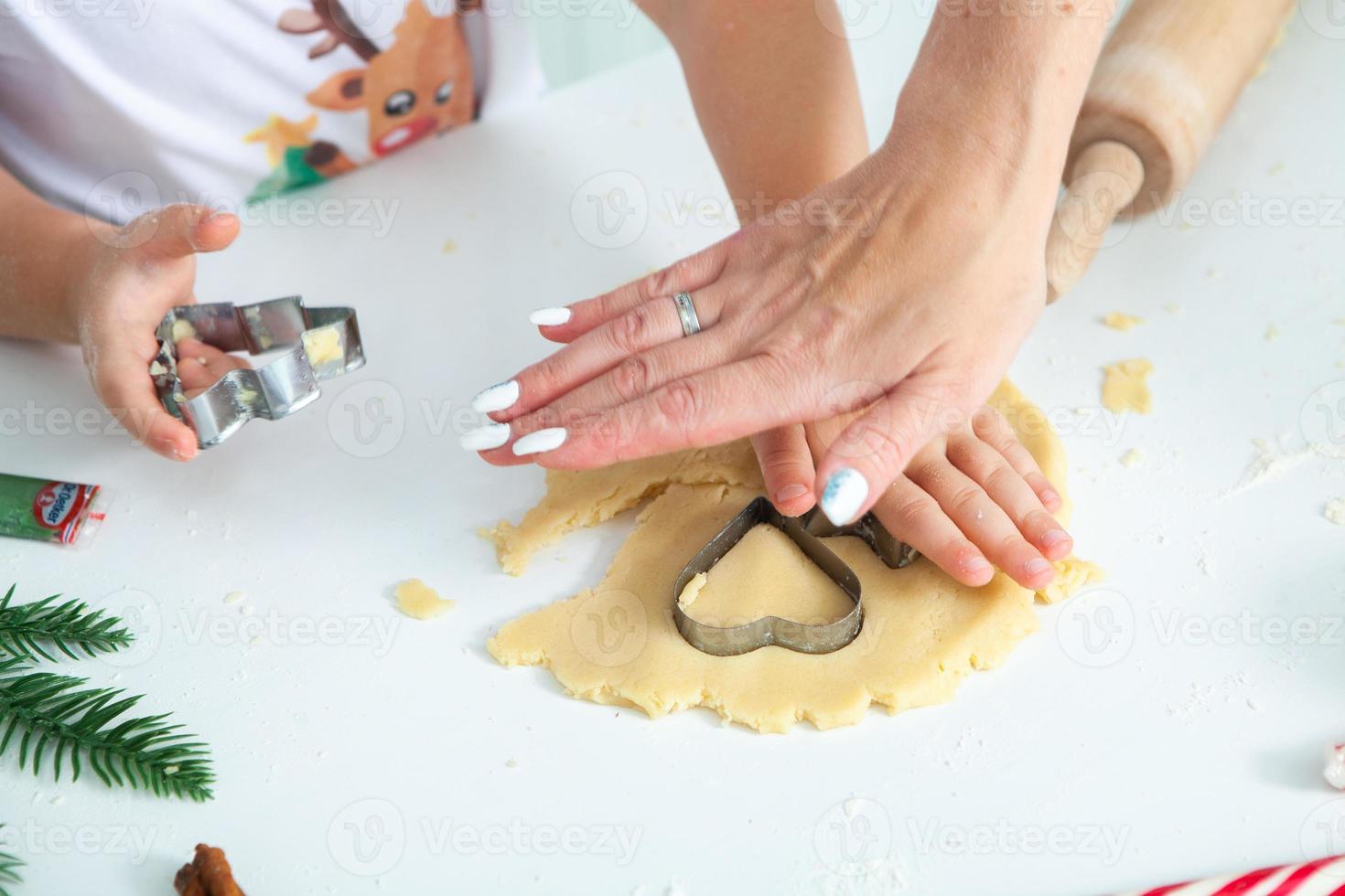 familia cocinando pasteles caseros. manos de mamás y niños sosteniendo cortadores de galletas. cocina familiar endecha plana. dulce hogar. concepto de felicidad. foto