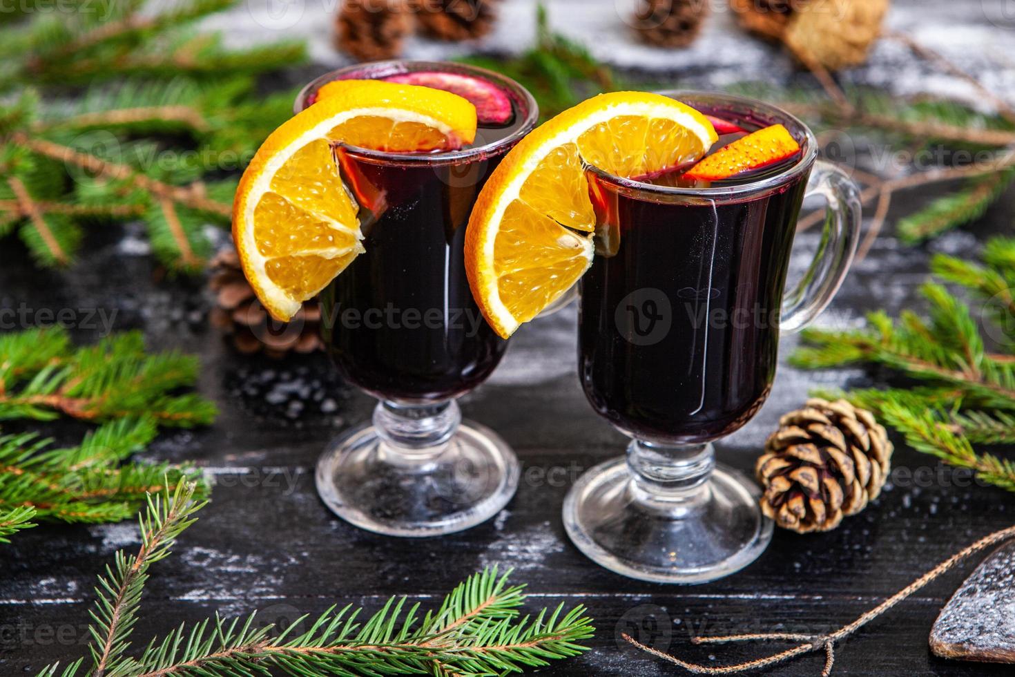 Glass of delicious glintwein or mulled hot wine, cinnamon, thread on vintage wooden background. photo