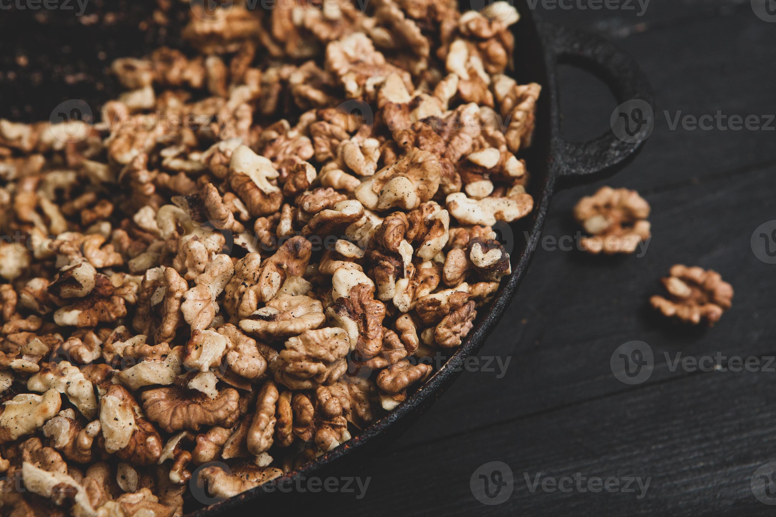 Walnut background. Peeled walnuts on a iron plate on black. walnuts a
