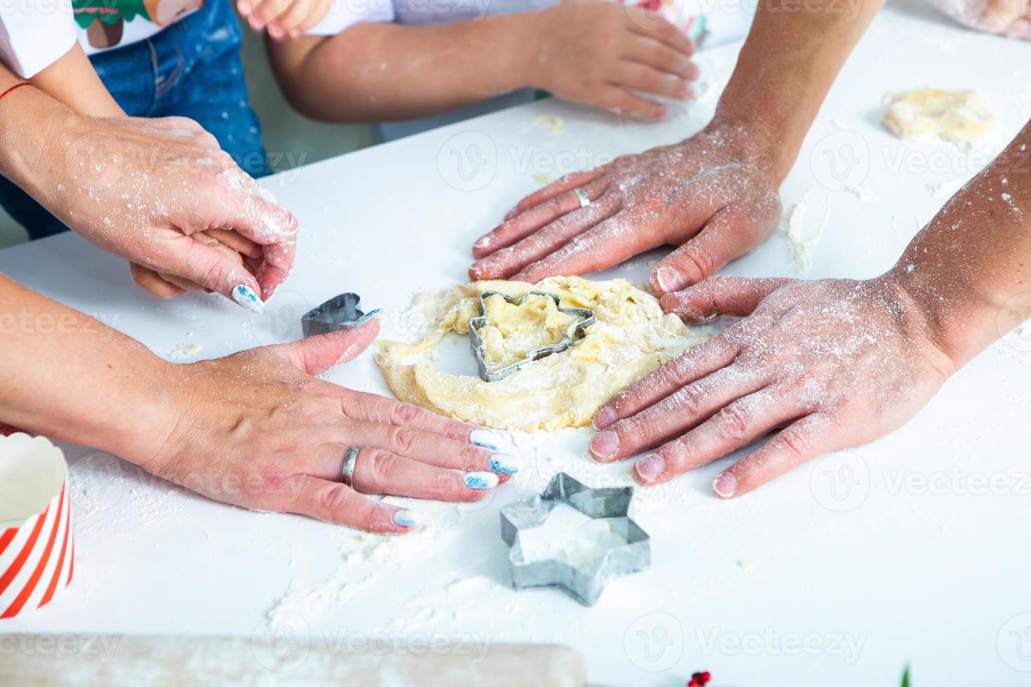 familia cocinando pasteles caseros. manos de mamás y niños sosteniendo cortadores de galletas. cocina familiar endecha plana. dulce hogar. concepto de felicidad. foto