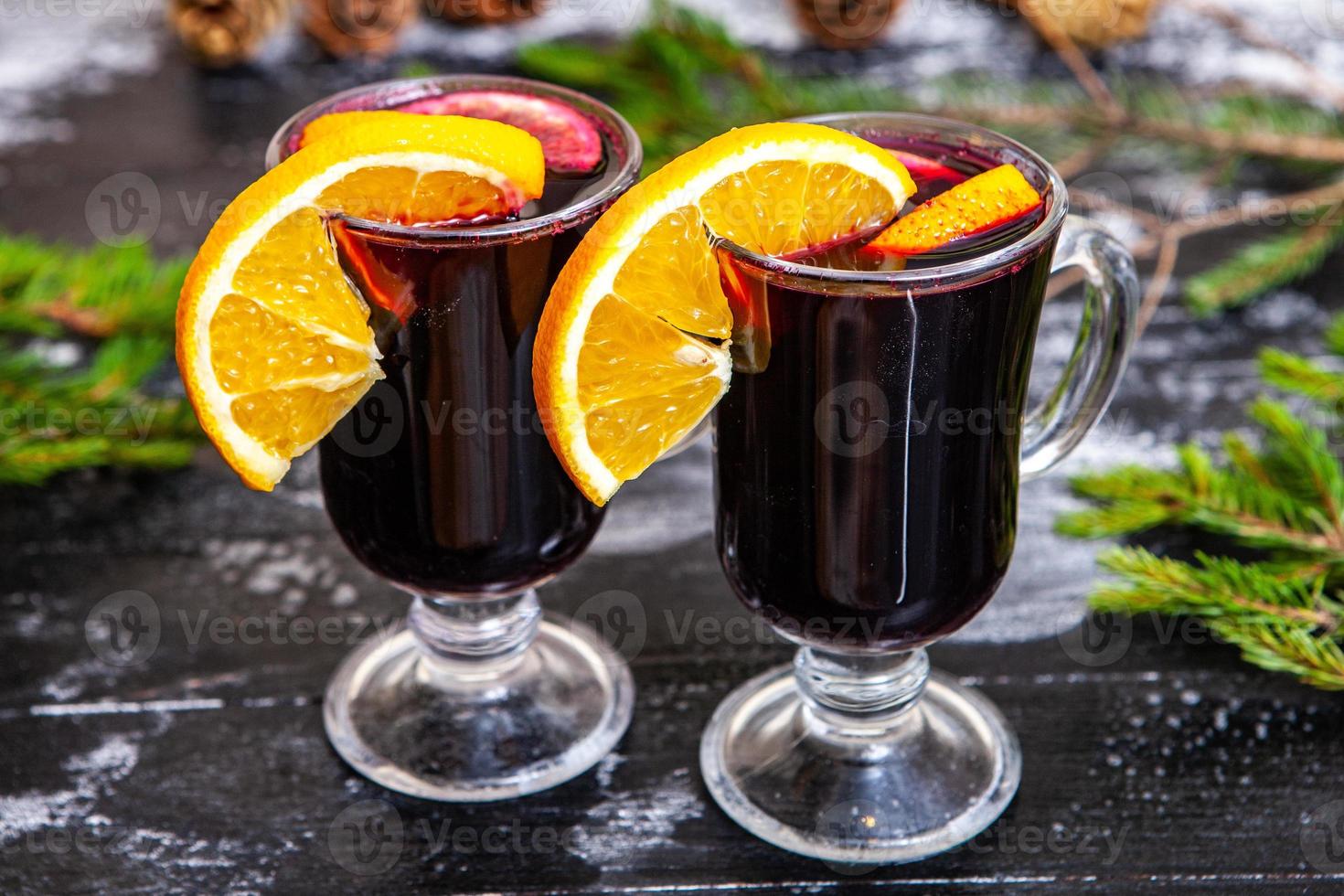 Glass of delicious glintwein or mulled hot wine, cinnamon, thread on vintage wooden background. photo