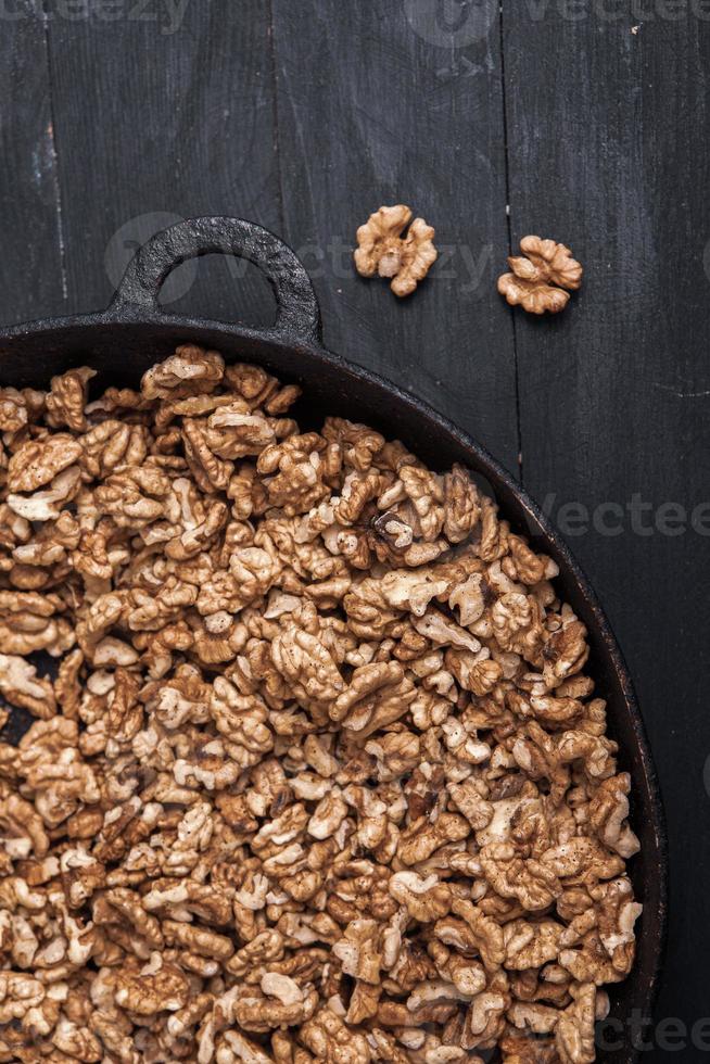 Walnut background. Peeled walnuts on a iron plate on black. walnuts a