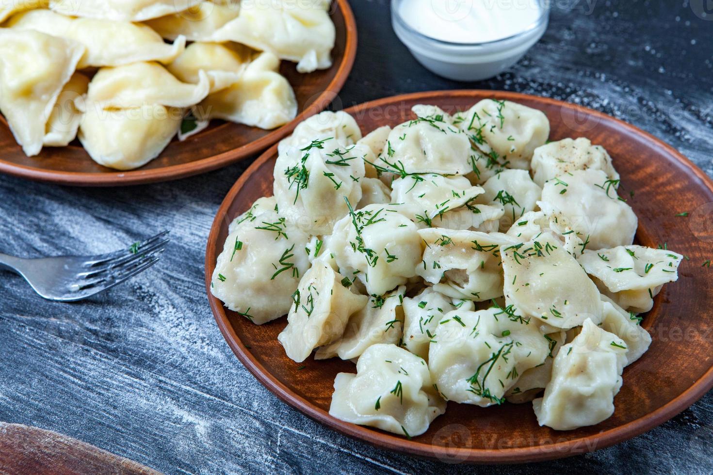 Traditional russian pelmeni or ravioli, dumplings with meat on wood black background. Russian food and russian kitchen concept. photo